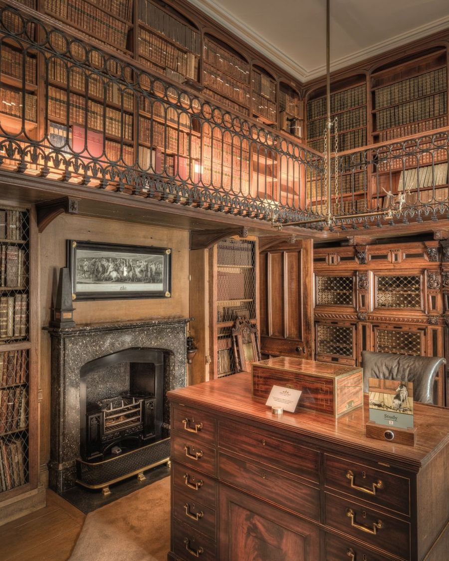 A wood-panelled private library with a fireplace and writing desk